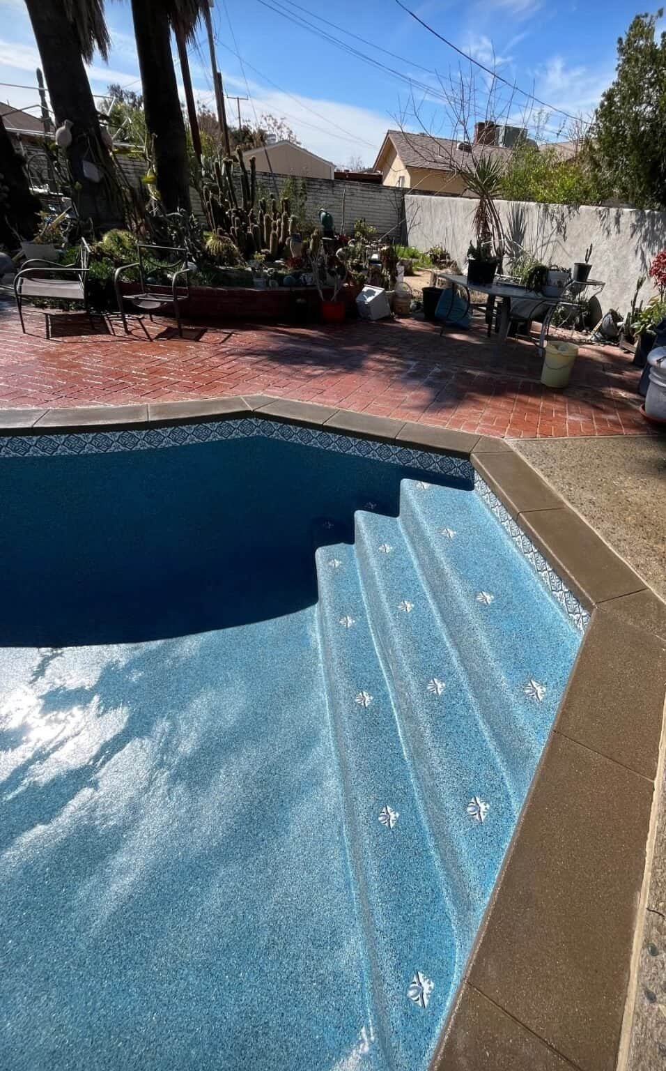 Beautiful backyard pool with new blue plaster finish and decorative tile steps.