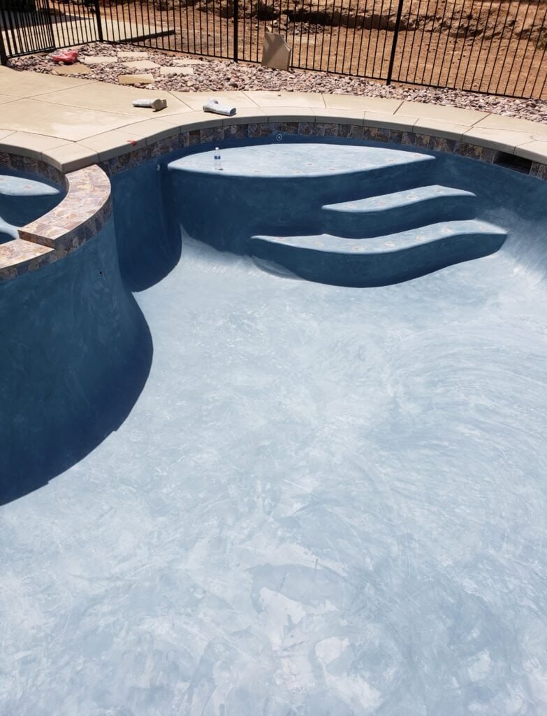 Custom pool with steps and high-quality plaster finish in backyard.
