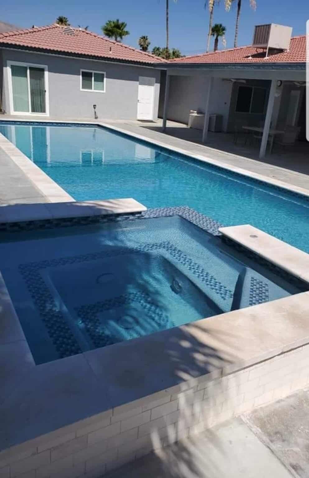 Pool with new smooth plaster finish and built-in hot tub in backyard.