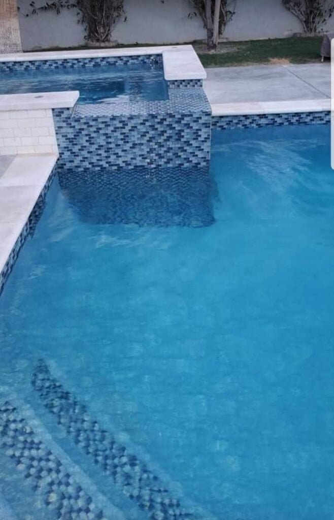 Custom pool plaster with blue mosaic tiles and smooth finish.