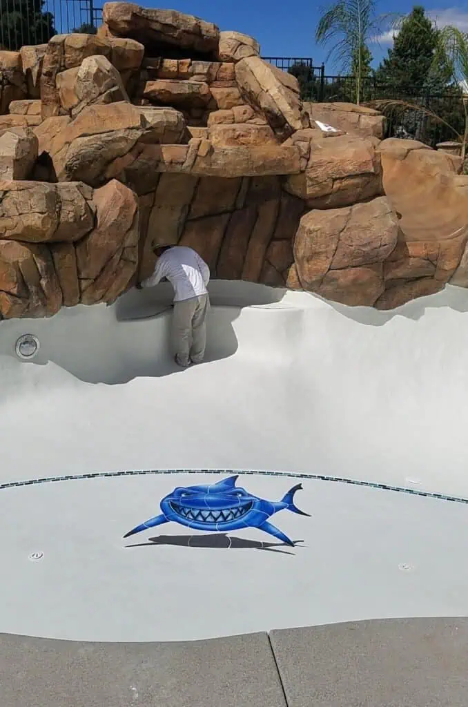 Custom pool waterfall with natural rock design and smooth white plaster finish.