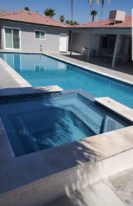Pool with new smooth plaster finish and built-in hot tub in backyard.
