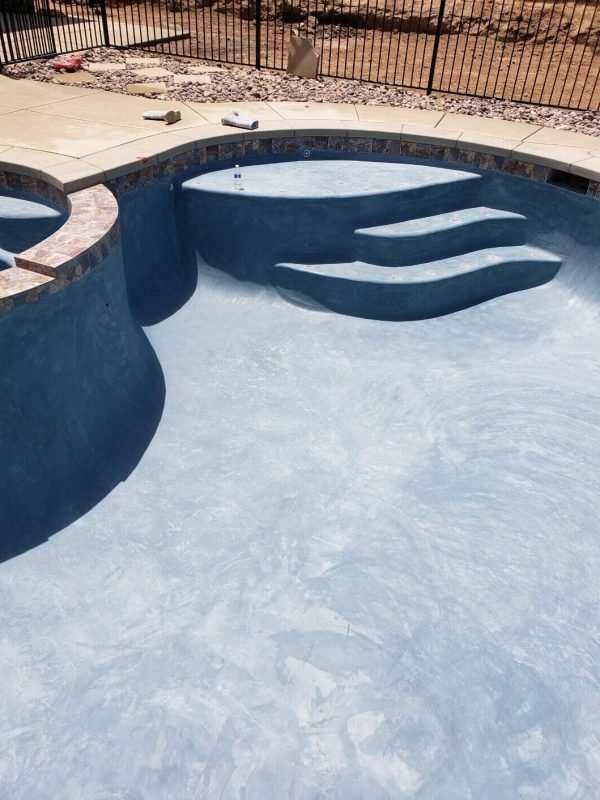Custom pool with steps and high-quality plaster finish in backyard.