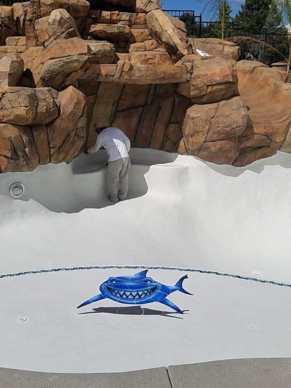 Custom pool waterfall with natural rock design and smooth white plaster finish.